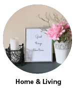 Candle in candleholder, picture frame with text-based artwork and metal vase with pink flower